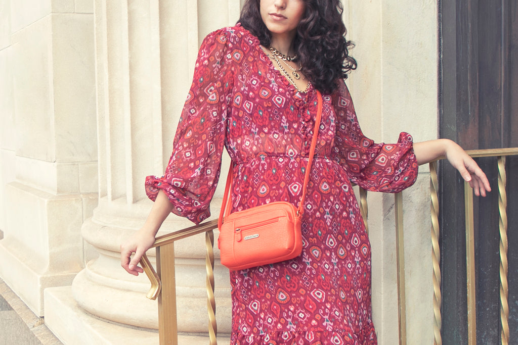 Gifts For Her Under $50 - Woman in a red dress with her orange mini dynamic crossbody bag.